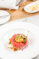 Steak tartare served in a restaurant with egg yolk,  onions, caper, mushroom and rocket salad