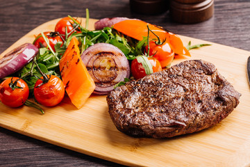 steakhouse porterhouse steak and colorful fresh roast vegetables  on a wooden board, view from above