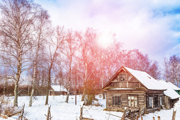 Winter landscape with old wooden house and trees with sunlight and blue cloudy sky. Amazing winter scene