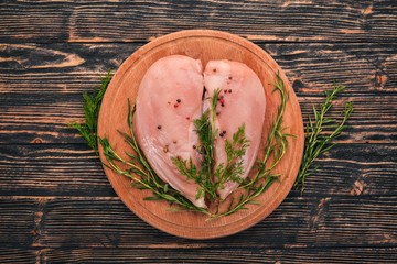 Raw chicken breast fillet with rosemary and spices on a black wooden background. Top view. Free space for text.