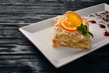 Layered cake with orange flavor. On a wooden background. Free space for your text. Top view.