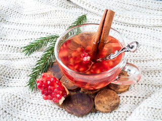 Fresh ripe pomegranate and red wine in a glass mug on a white knitted blanket