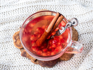 Fresh ripe pomegranate and red wine in a glass mug on a white knitted blanket