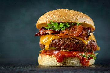 Burger with cheese and bacon on a dark background - obrazy, fototapety, plakaty