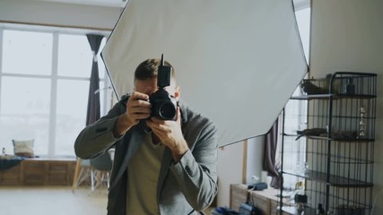 Young man photographer working in a photo studio taking photos of model on digital camera - Powered by Adobe