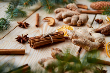 Obraz na płótnie Canvas New year background with traditional spices ginger, dried oranges, apples, cinnamon sticks, anise stars. Ingredients for cooking or mulled wine. New year bakery with Christmas tree branches. Side view