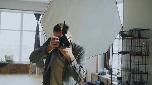 Young man photographer working in a photo studio taking photos of model on digital camera