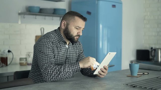 Young man doing online shopping with tablet sitting at home
