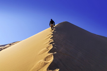 A man walking along the ridge of the Singing Barkhan. Nature reserve Altyn Emel. Kazakhstan