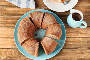 Plate with delicious cinnamon roll cake on table