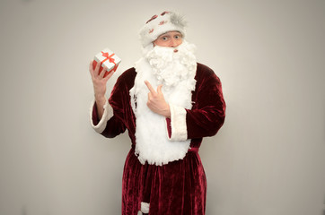 Santa Claus holds in hands Christmas present box isolated on gray background.
