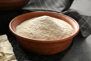 Fototapeta na wymiar Bowl with buckwheat flour on table