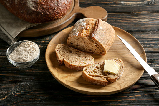 Wooden plate with buckwheat bread on table