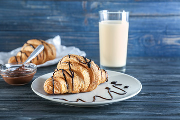 Plate with sweet croissant on table