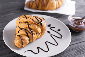 Plate with sweet croissant on table