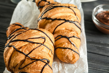 Delicious croissants with chocolate syrup on table