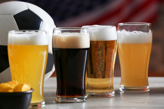 Glasses with different sorts of beer on table in football bar