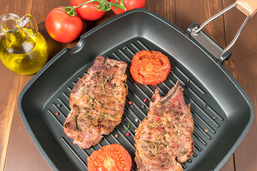 Grilled steak on grill pan with tomatoes on dark background