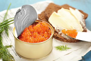 Tin can with delicious red caviar, dill and sandwich on table