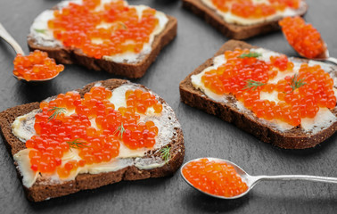 Tin can with delicious red caviar, dill and sandwich on table