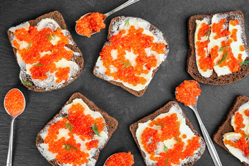 Tin can with delicious red caviar, dill and sandwich on table
