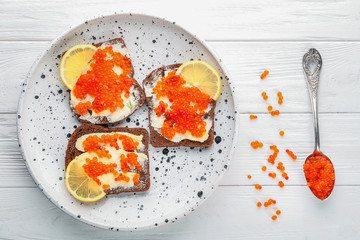 Tin can with delicious red caviar, dill and sandwich on table
