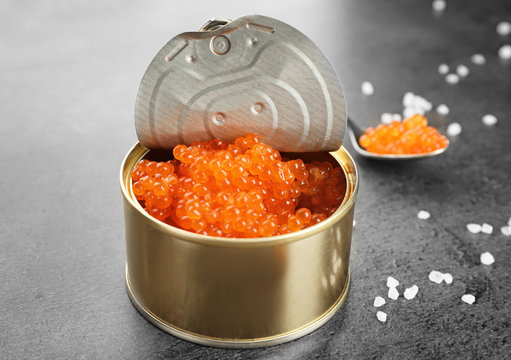 Tin can with delicious red caviar, dill and sandwich on table