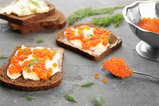 Tin can with delicious red caviar, dill and sandwich on table