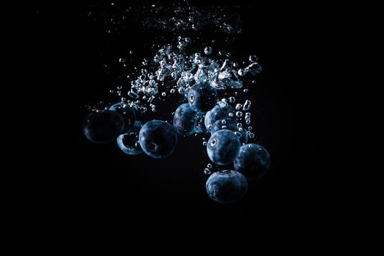 Blueberries falling into a water black background