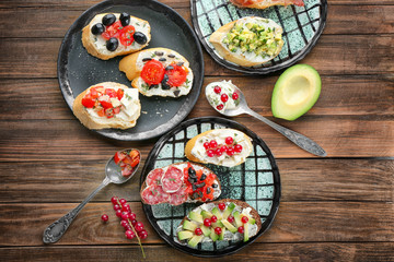 Plates with tasty bruschettas on wooden background