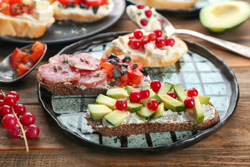 Plate with tasty bruschettas on table