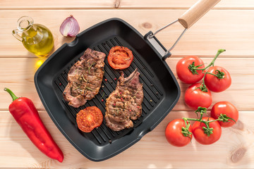 Grilled steak on grill pan with tomatoes on wooden background