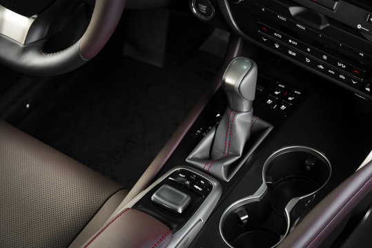 Automatic transmission gear shift of a modern car, car interior details with electronic components, red leather with a stitch