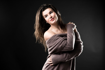 Sensitive woman dressed in knitted warm sweater on dark background