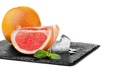 Whole grapefruit and two slices with leaf of mint on the slate p