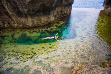 Naklejka premium Woman swimming in Angel's Billabong is natural infinity pool on the island of Nusa Penida next to Bali, Indonesia