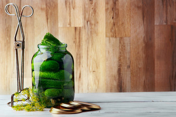 Jar with cucumbers, covers and tool for conservation.Wooden background .Free sapce.Horizontal shot