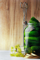 Jar with cucumbers, covers and tool for conservation.Wooden background .Free space.Vertical shot