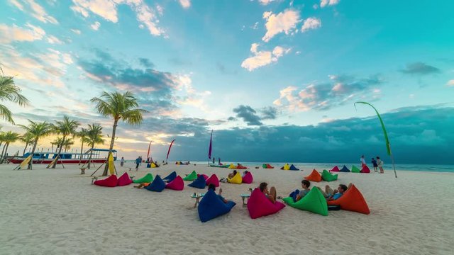 Timelspae People lie on a white beach on pillows and meet the sunset on the island Nusa Lembongan, Bali, Indonesia