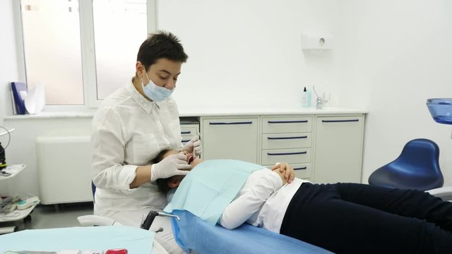 Dentist examining a teeth of little girl. Dentist using a mirror and dental proba. Camera movement. A dentist with surgey and gloves.