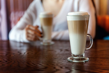 Latte macchiato in tall glass close up. Coffee on a table in cafe