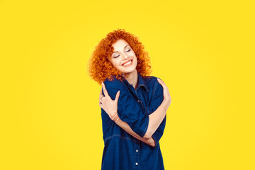  Love yourself concept. Closeup portrait confident smiling woman holding hugging herself isolated yellow wall background. Positive human emotion, facial expression feeling reaction situation attitude