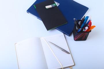 Colorful notebooks and office supplies on white table.