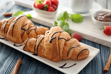 Plate with tasty croissants on table, closeup