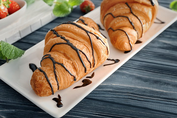 Plate with tasty croissants on table, closeup