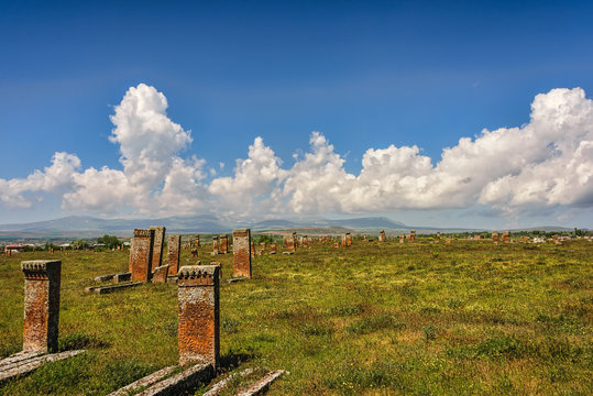 Medieval graveyard in greenery under blue skies with fluffy whit
