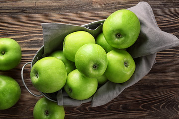 Basket with fresh green apples on wooden background