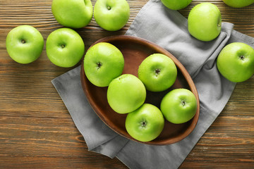 Plate with fresh green apples on wooden background
