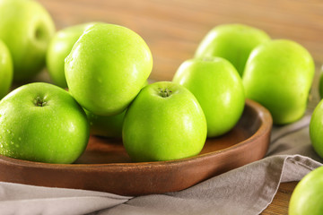 Plate with fresh green apples on wooden table, closeup