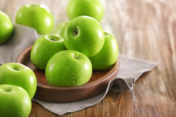 Plate with fresh green apples on wooden background